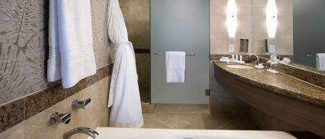 A modern bathroom with a bathtub, two sinks, and a large mirror.