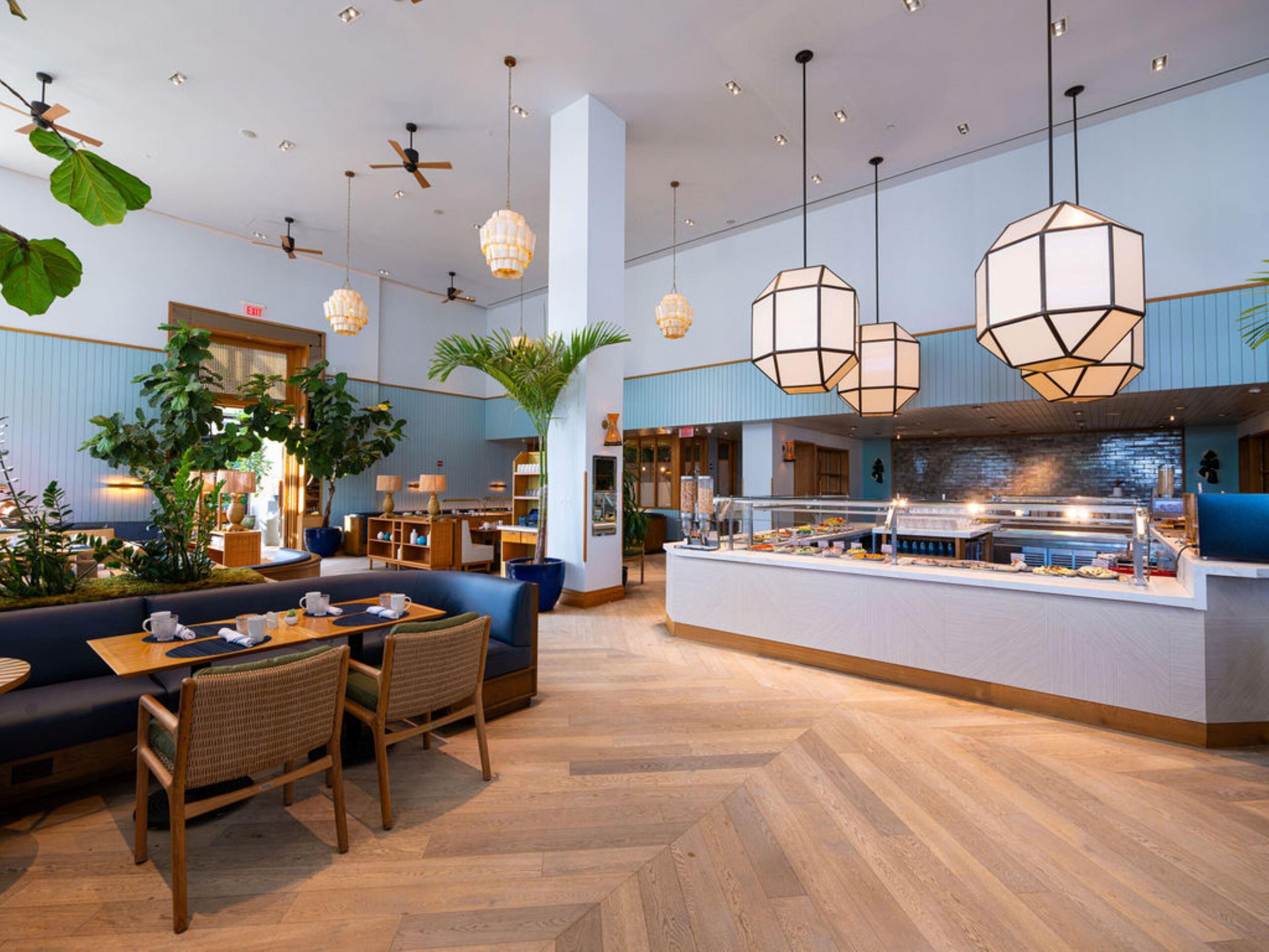 A modern hotel lobby with seating, a buffet, and ceiling fans.