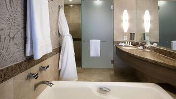 A modern bathroom with a bathtub, two sinks, a glass shower enclosure, and a large mirror.