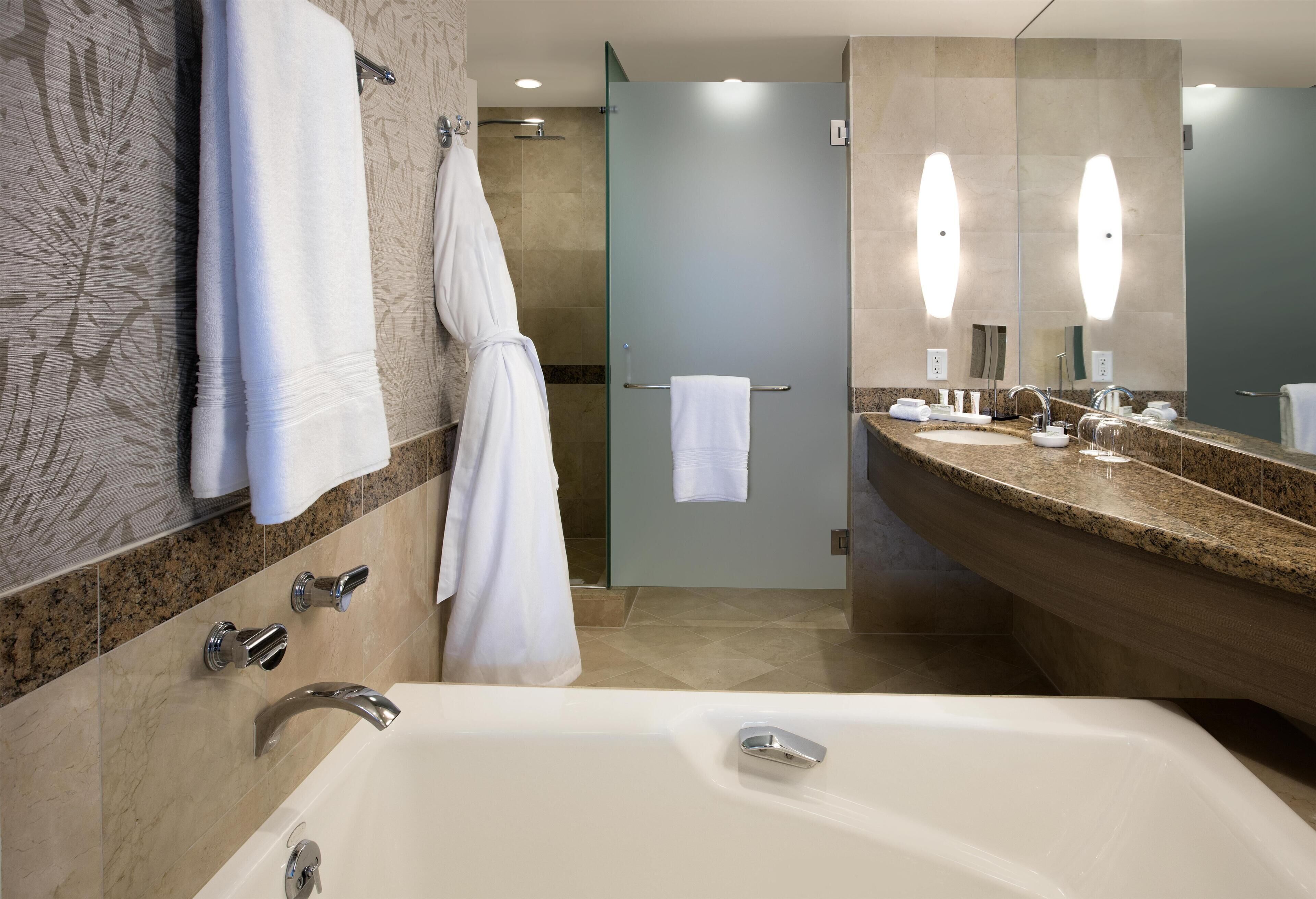 Un baño moderno con una bañera grande, cabina de ducha de vidrio y tocador con espejo.