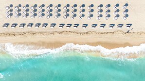A beach with rows of umbrellas and lounge chairs, a sandy shore, and a view of turquoise water. - Signia by Hilton Diplomat Beach Resort (Hollywood)