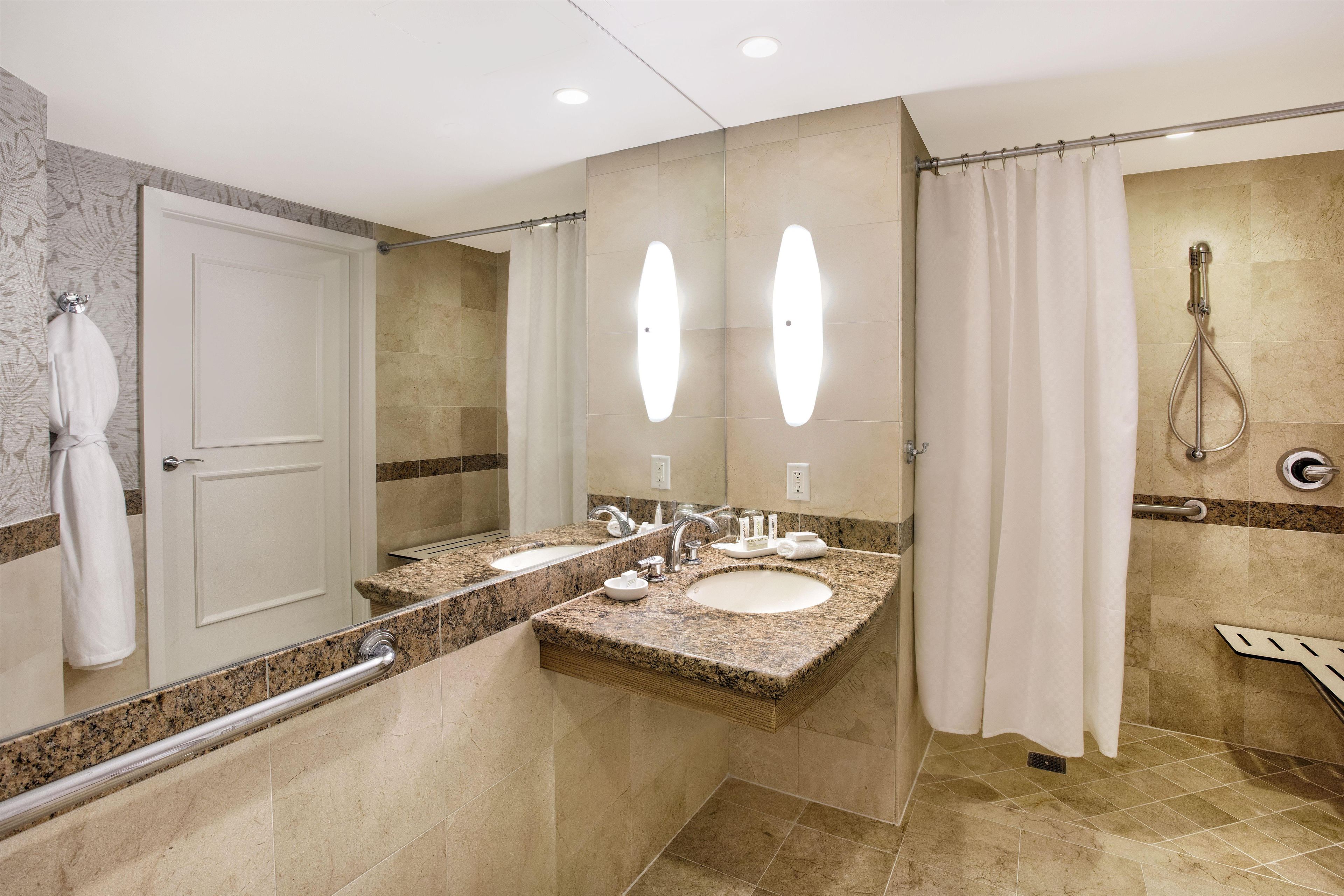 Un baño de hotel con dos lavamanos, una ducha y un espejo.