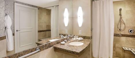 Un baño de hotel con dos lavamanos, una ducha y un espejo.