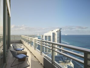 Un balcón con vistas al océano, un paisaje urbano y un edificio alto.