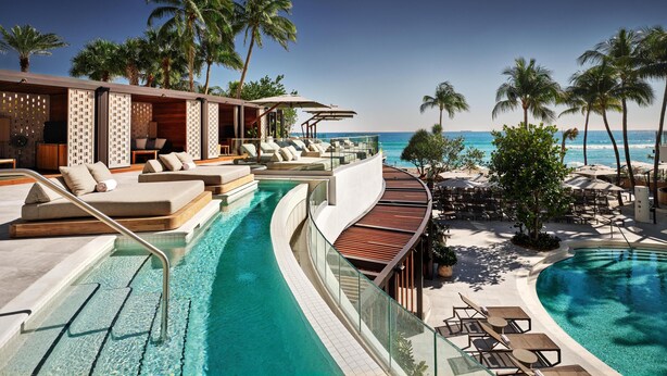 A poolside area with lounge chairs, a pool, and a view of the ocean. - Signia by Hilton Diplomat Beach Resort (Hollywood)