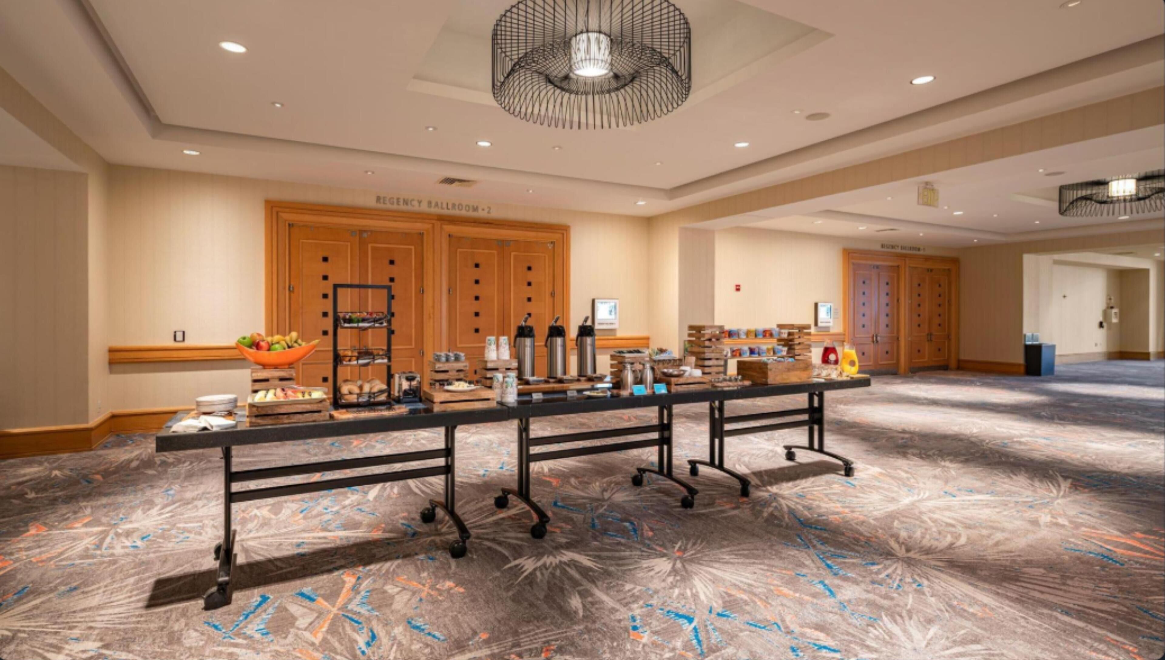 A conference room with a long table set up for a buffet, equipped with various food and beverage stations.