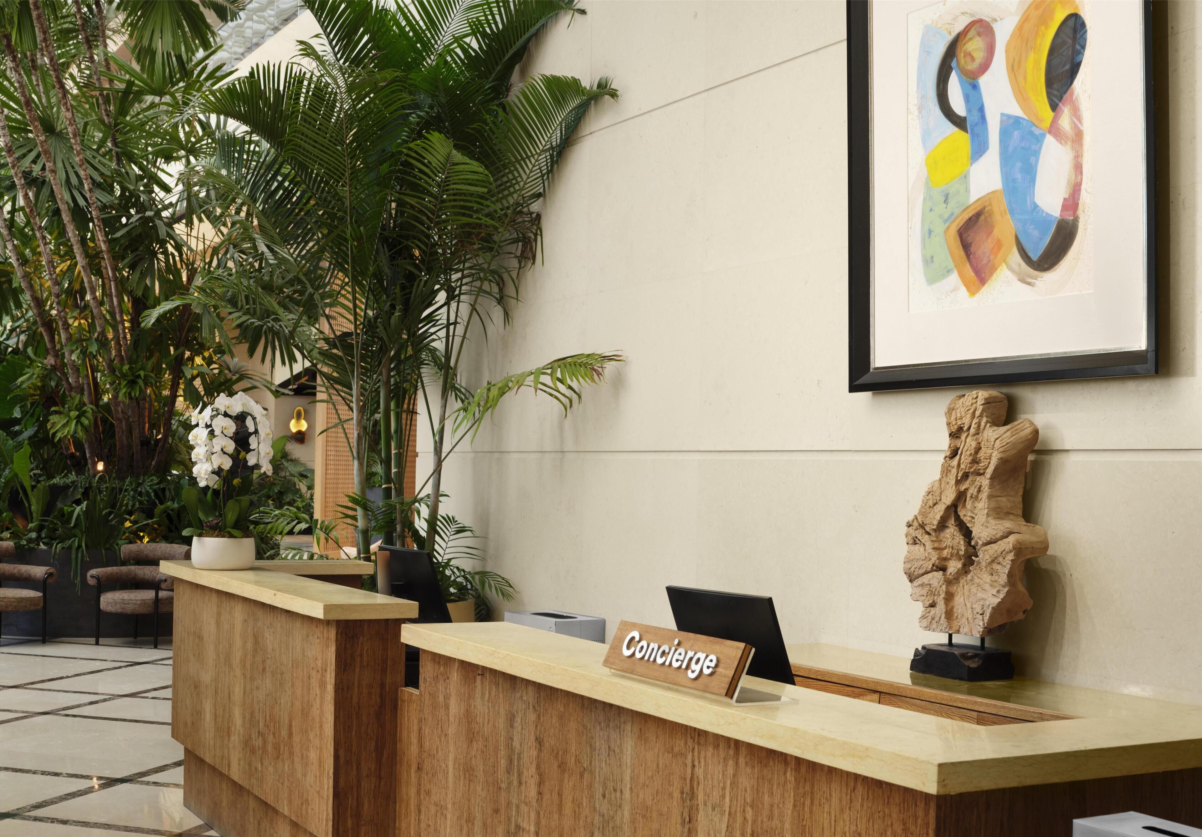 Un comptoir d’accueil avec une pancarte indiquant « Concierge », une sculpture et un tableau abstrait encadré.