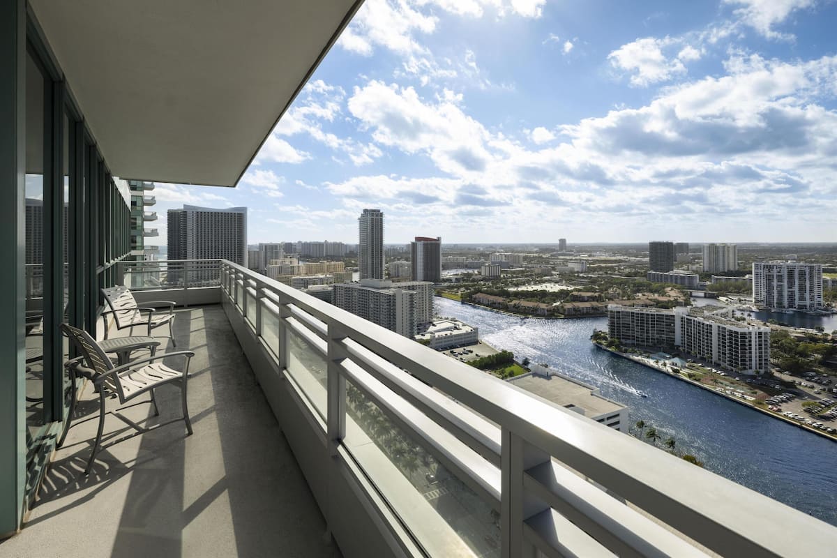 A balcony with a view of a river and cityscape, featuring modern buildings and a clear sky.