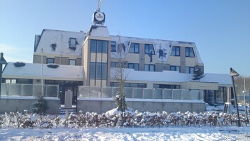 Un edificio moderno con techo plano, ventanas grandes y suelo cubierto de nieve.