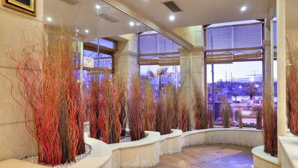 A lobby with a curved seating area, large windows, and decorative plants. - Hotel Kennedy Nova (Gzira)