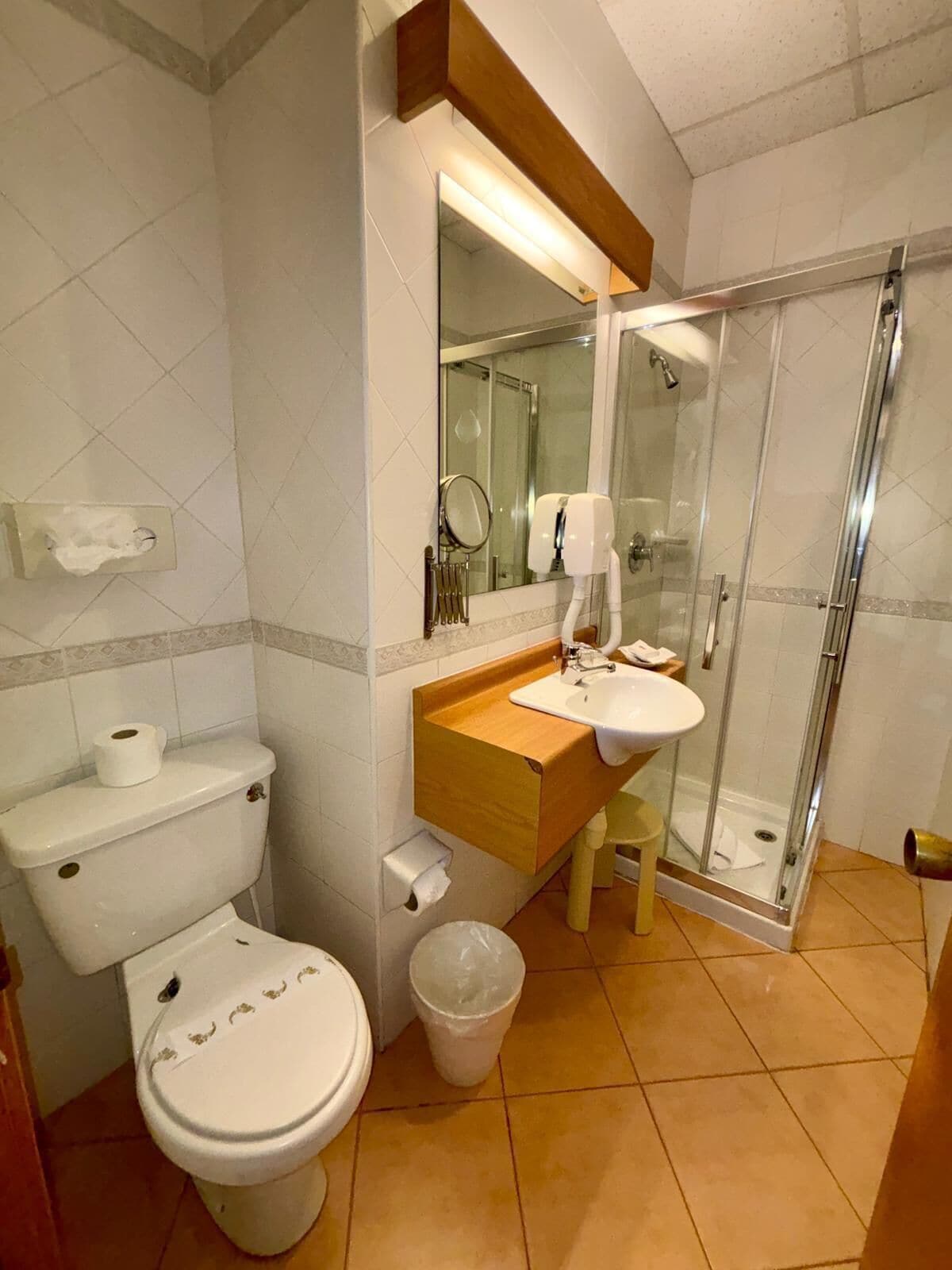 Un baño con inodoro, lavamanos y cabina de ducha de vidrio.
