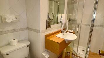 Un baño con inodoro, lavamanos y cabina de ducha de vidrio.