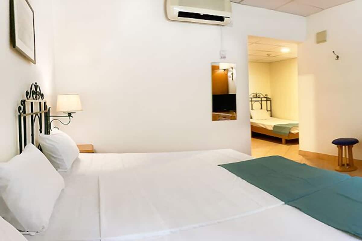 A hotel room with a bed, a desk, a chair, a wardrobe, and a television.