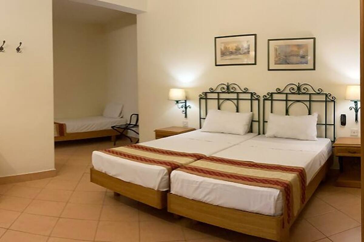 A hotel room with a bed, desk, chair, TV, and two bedside lamps.
