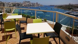 A terrace with outdoor seating overlooking a marina with boats. - Hotel Kennedy Nova (Gzira)