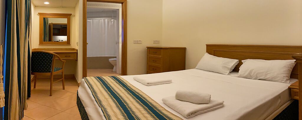 Une chambre d’hôtel avec un lit, un bureau, une chaise et une salle de bain.