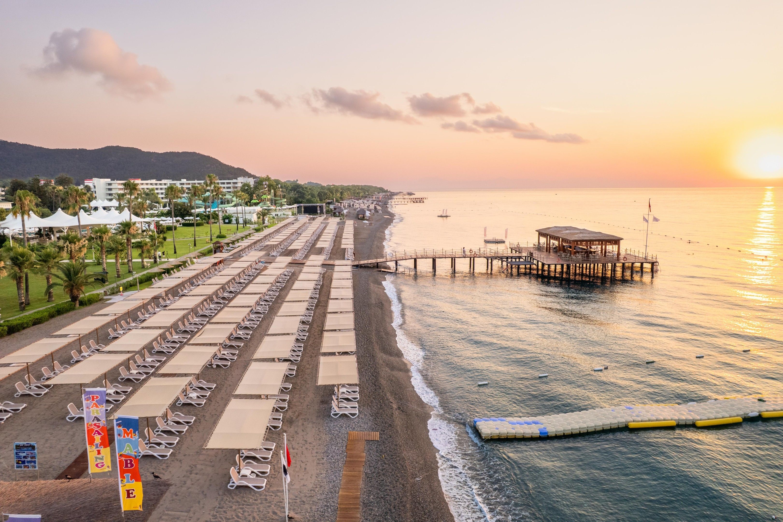 A beach with rows of sun loungers and a pier extending into the sea.