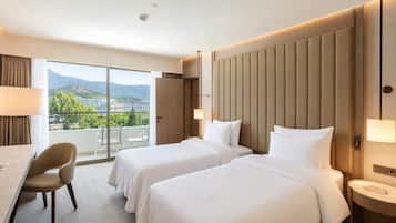 Een hotelkamer met twee bedden, een bureau, een stoel en uitzicht op het omliggende landschap.