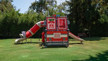Un parque infantil con un tobogán y una estructura de juego con temática de bomberos.