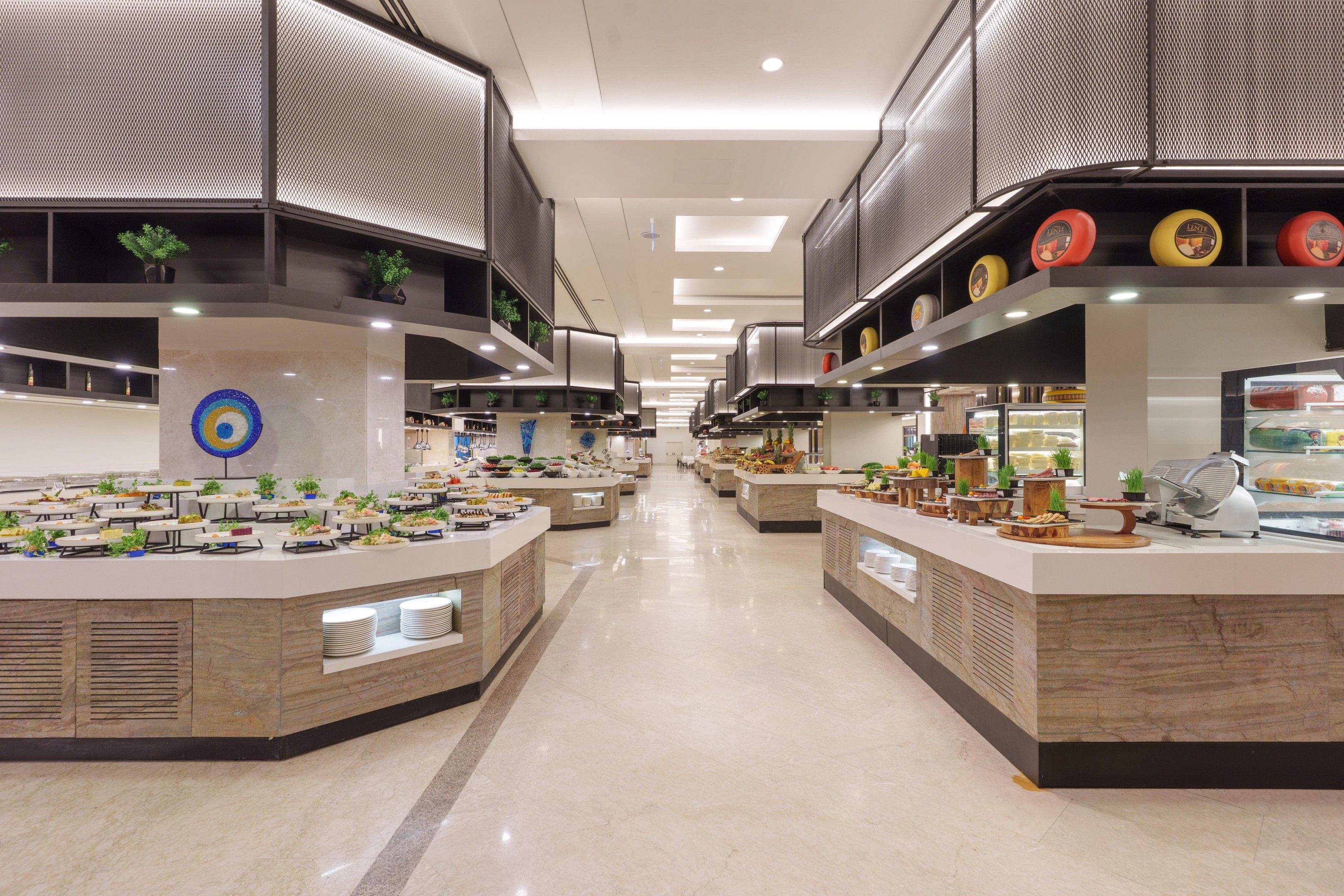 Ein modernes Buffet mit mehreren Servierstationen, einem zentralen dekorativen Element und einer sauberen, gut beleuchteten Umgebung.