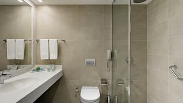 A modern bathroom with a glass shower enclosure, a white sink, and a toilet.