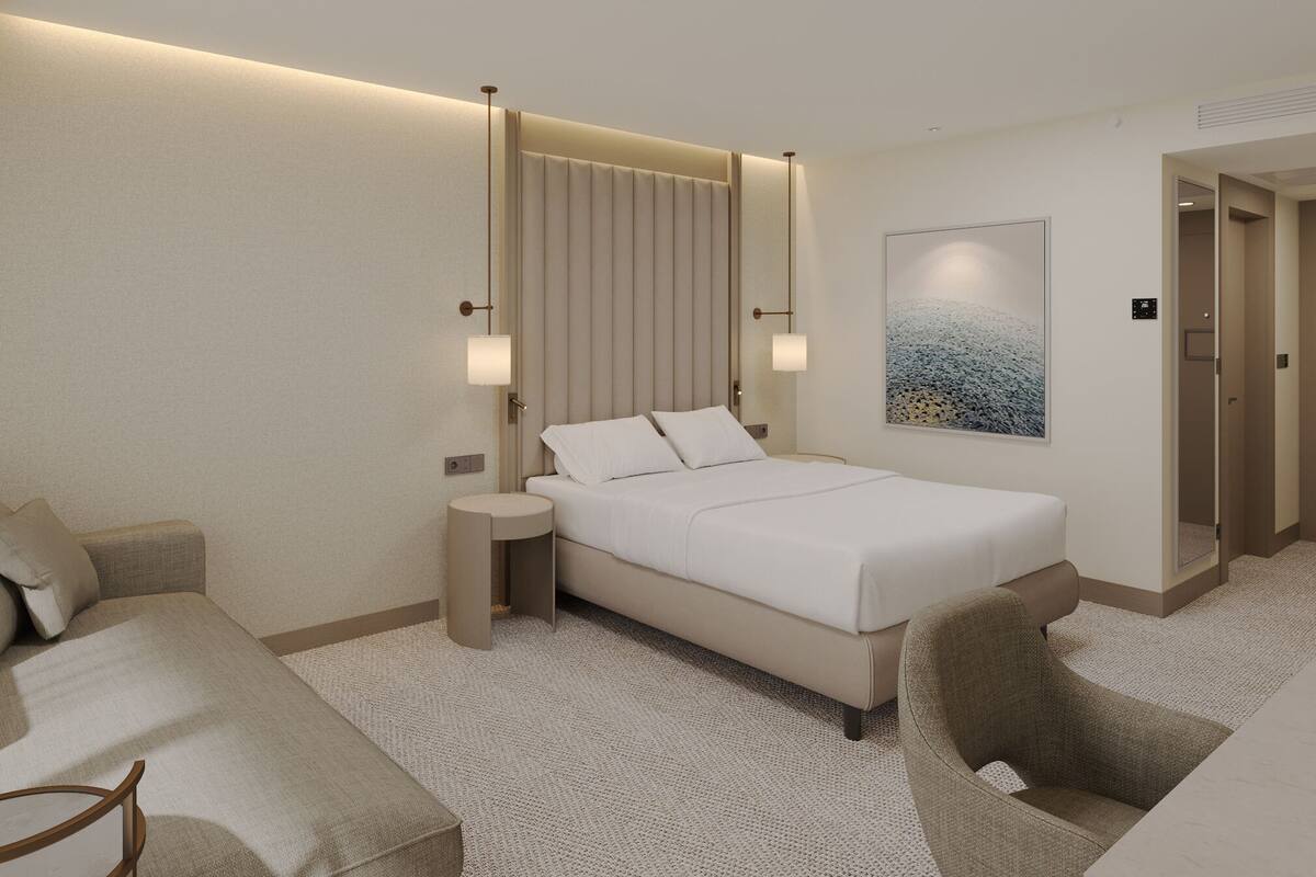 A modern hotel room with a bed, a sofa, a chair, a nightstand, and a painting on the wall.
