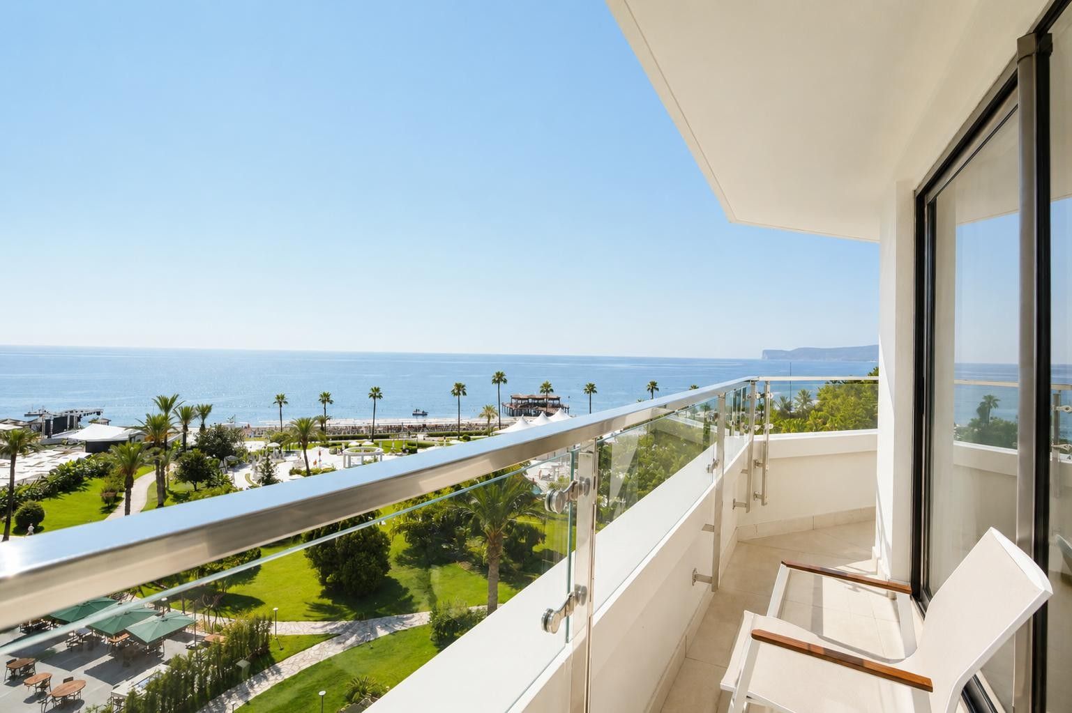 A balcony with a clear view of the sea and a resort area.