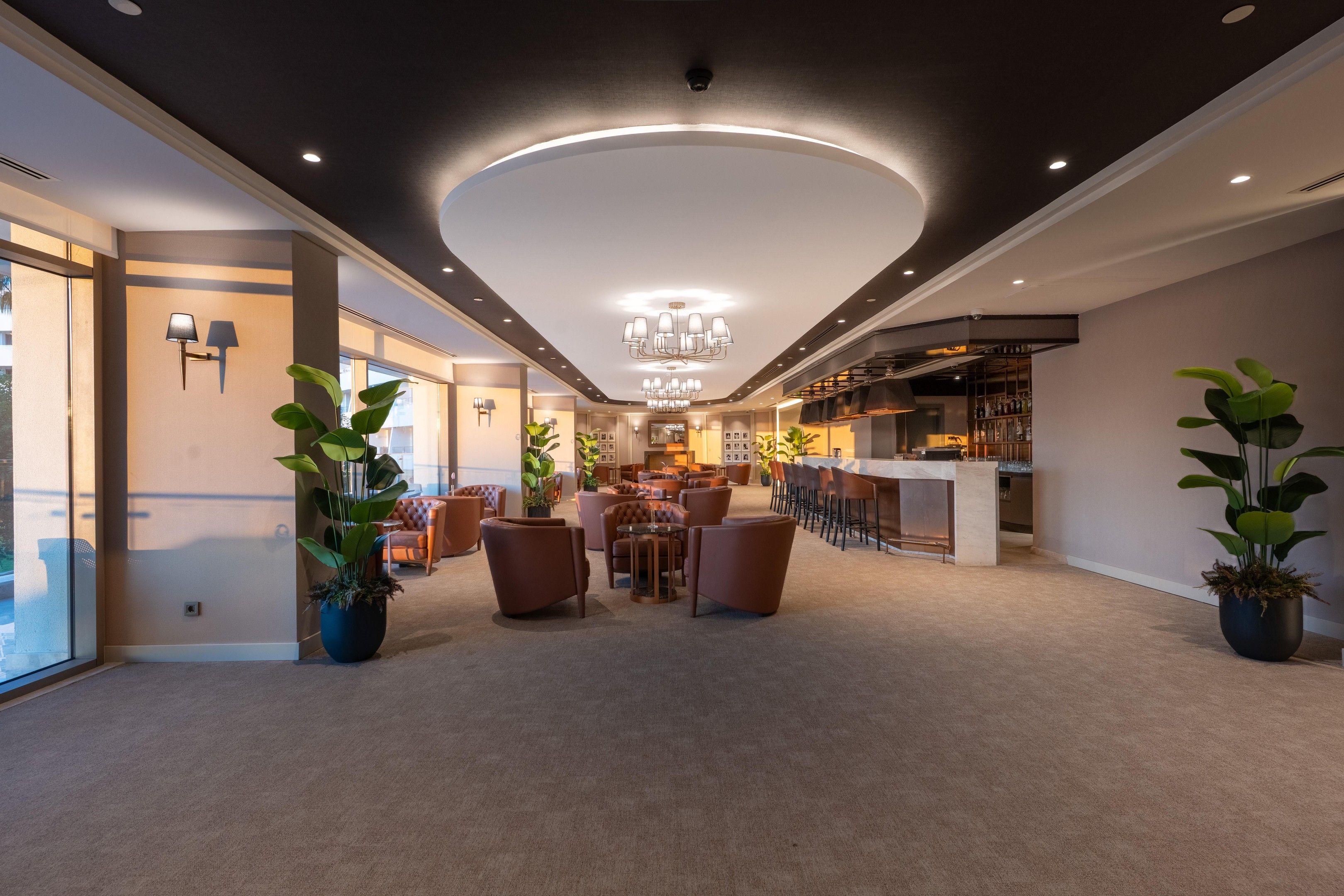 A modern hotel lobby with a bar area, seating, and potted plants.
