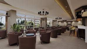 A spacious lounge area with multiple seating options, large windows offering views, and a modern chandelier. -  Mirage Park Resort - Premium All Inclusive (Kemer)