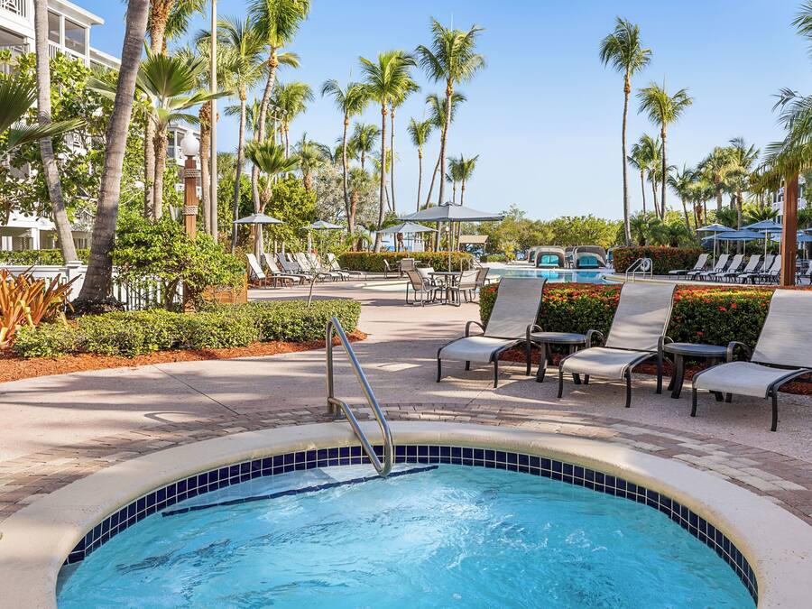 A pool area with lounge chairs, palm trees, and a tiled pool.