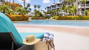 Un área de descanso junto a la piscina con una silla de mimbre, un sombrero de paja y un bolso de playa.