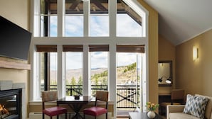 A spacious living room with a fireplace, a dining table with chairs, a sofa, and a balcony with a view of the mountains. - The Residences at Mountain Lodge, Beaver Creek by Hyatt Vacation Club (Avon)