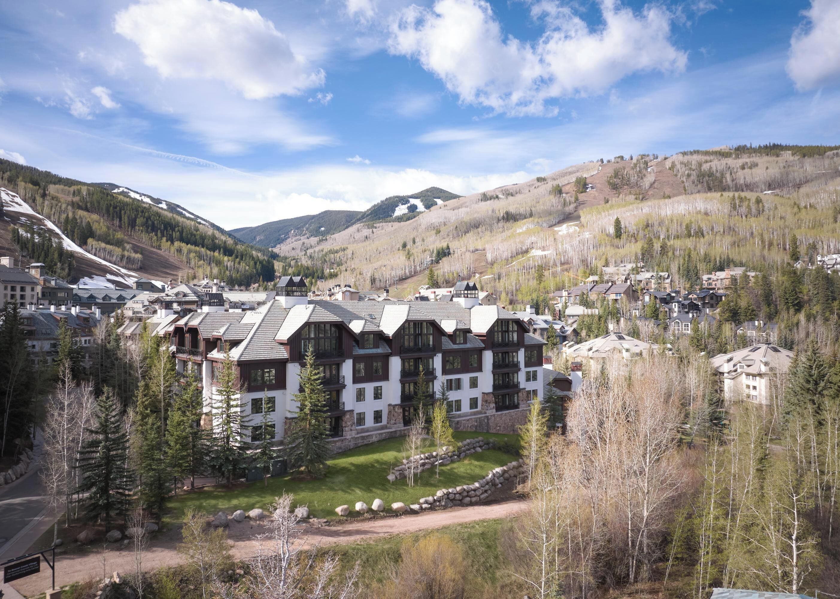 A lodge with multiple floors, surrounded by a mountainous landscape and sparse trees.
