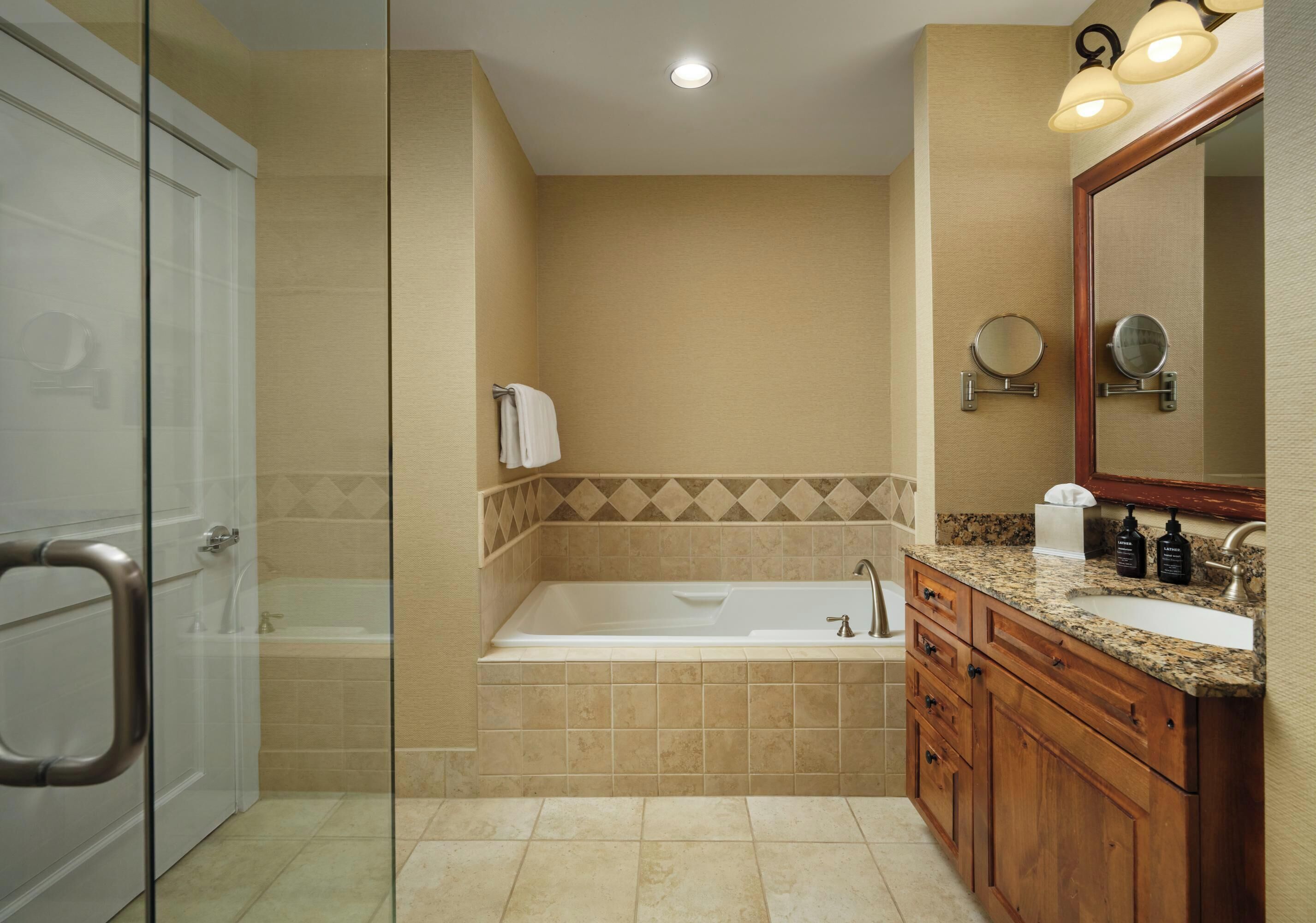 Une salle de bain avec une porte de douche en verre, une baignoire, un meuble-lavabo et un miroir.