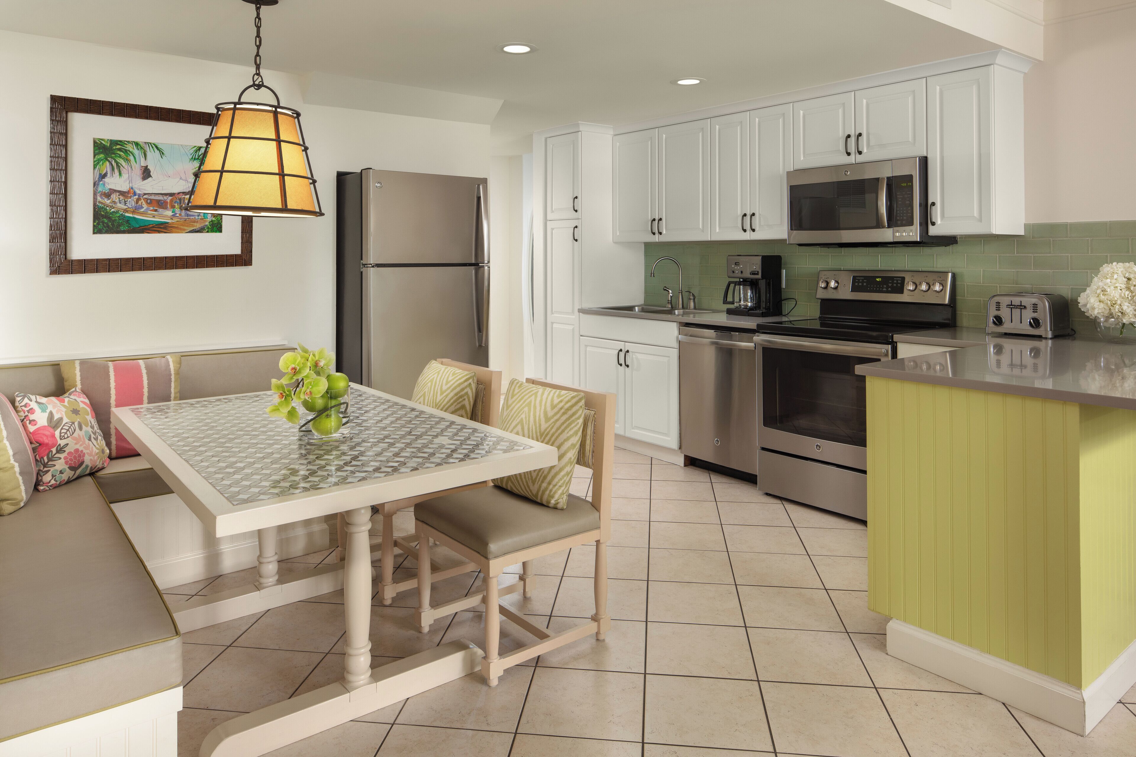 A modern kitchen with white cabinets, stainless steel appliances, and a green island.