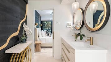 A modern bathroom with a white vanity, gold fixtures, and a large mirror.
