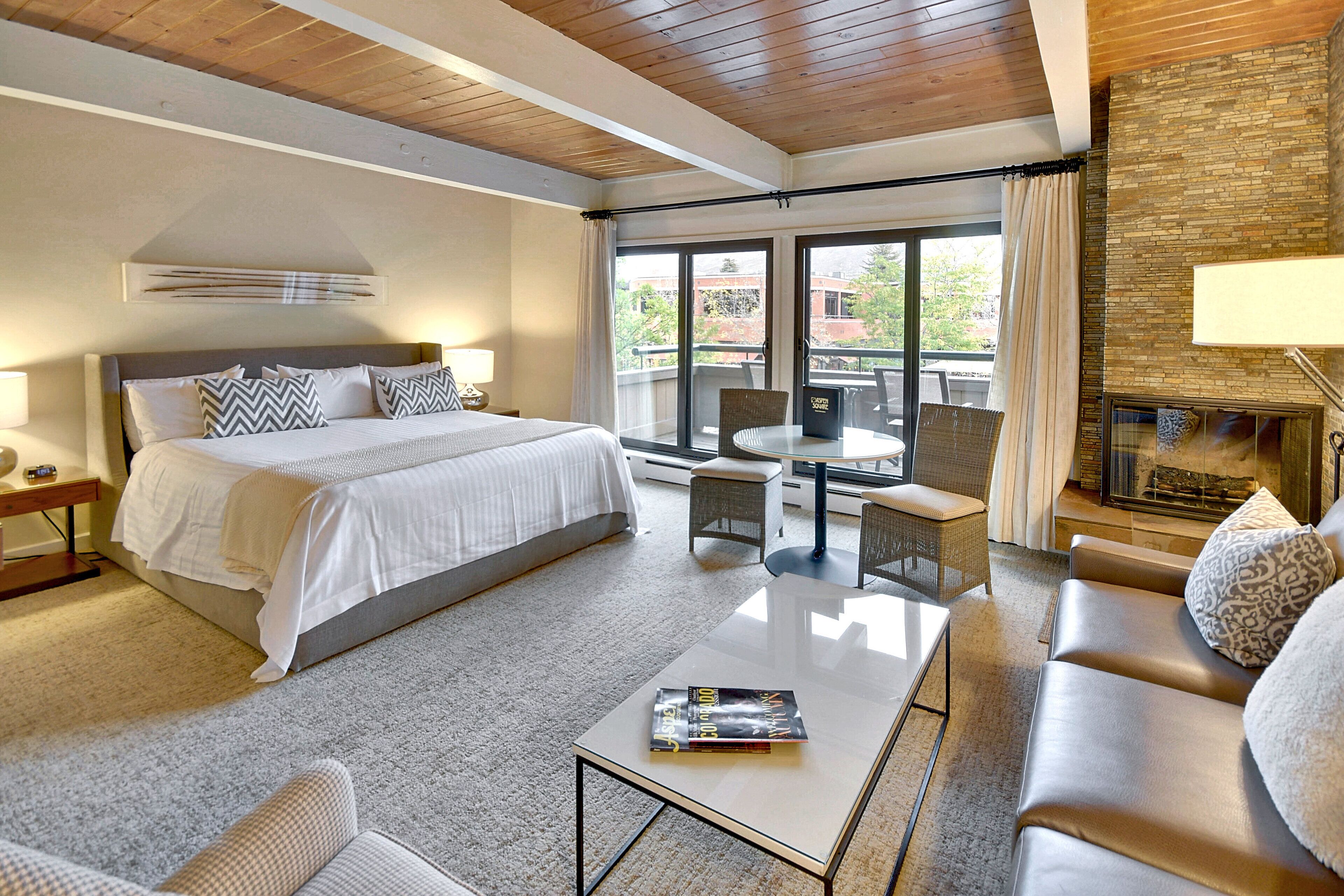 Ein Hotelzimmer mit einem großen Bett, einem Schlafsofa, einem Couchtisch, einem Kamin und einem Balkon mit Blick ins Freie.