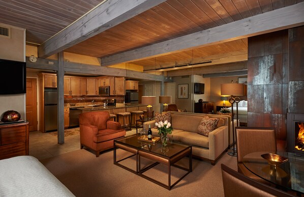 A spacious living area with a fireplace, a kitchen in the background, and a cozy seating arrangement. - Aspen Square Condominium Hotel (Aspen)