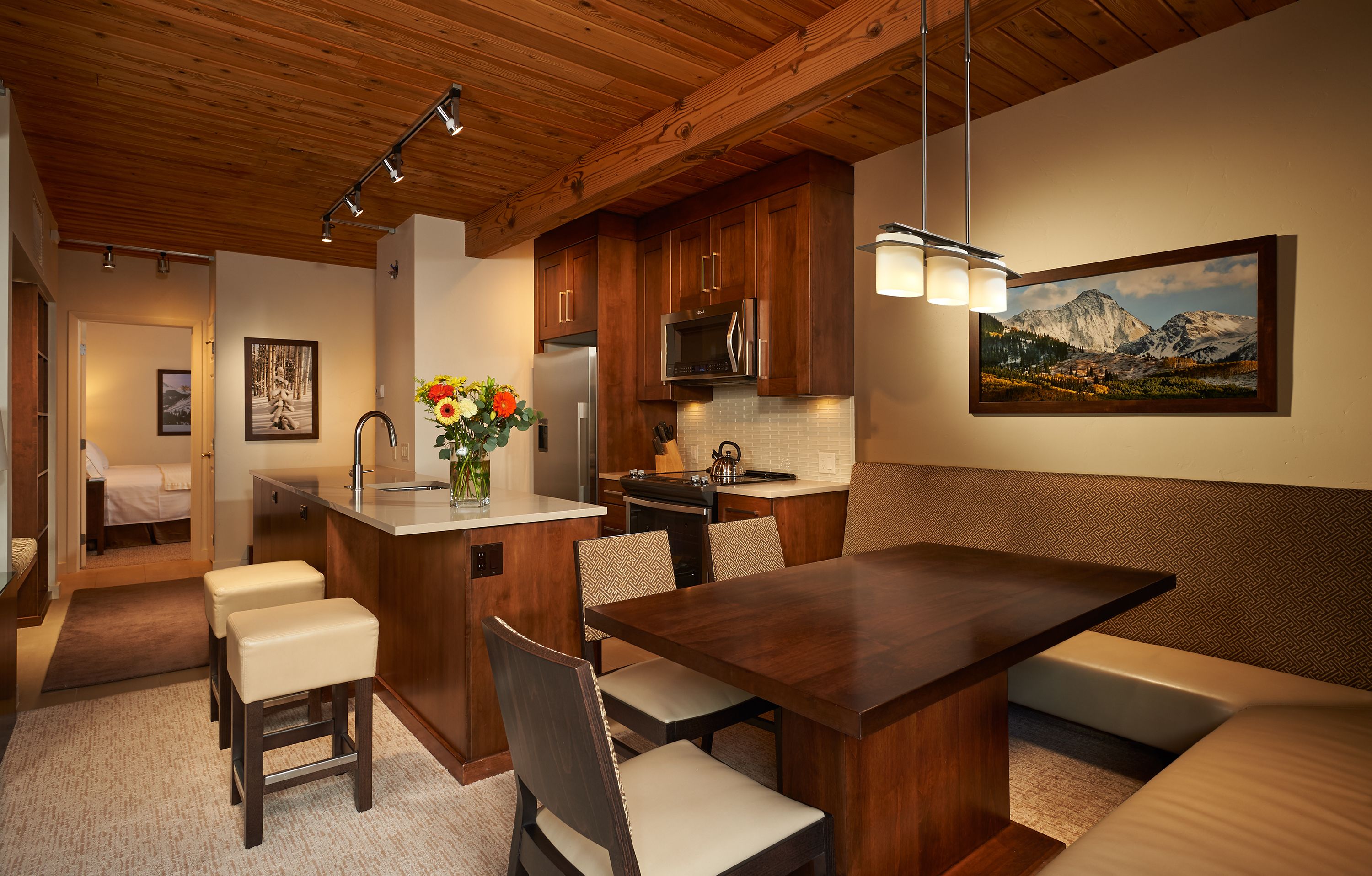 A modern kitchen with wooden cabinets, a central island, and a dining area with a bench.