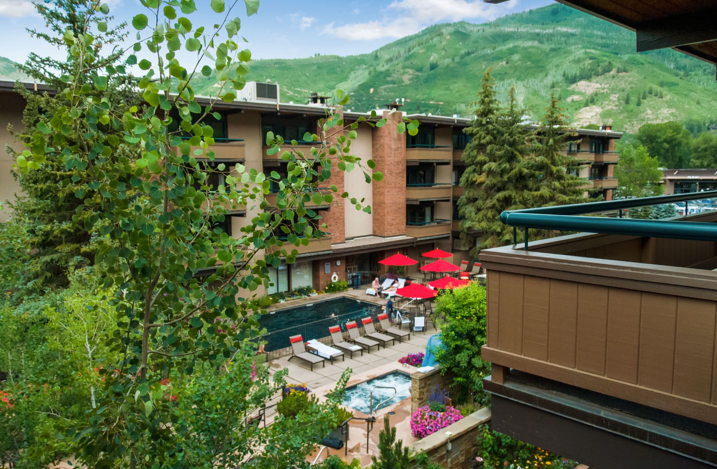 Un hotel con area piscina, posti a sedere all'aperto e uno sfondo montuoso.
