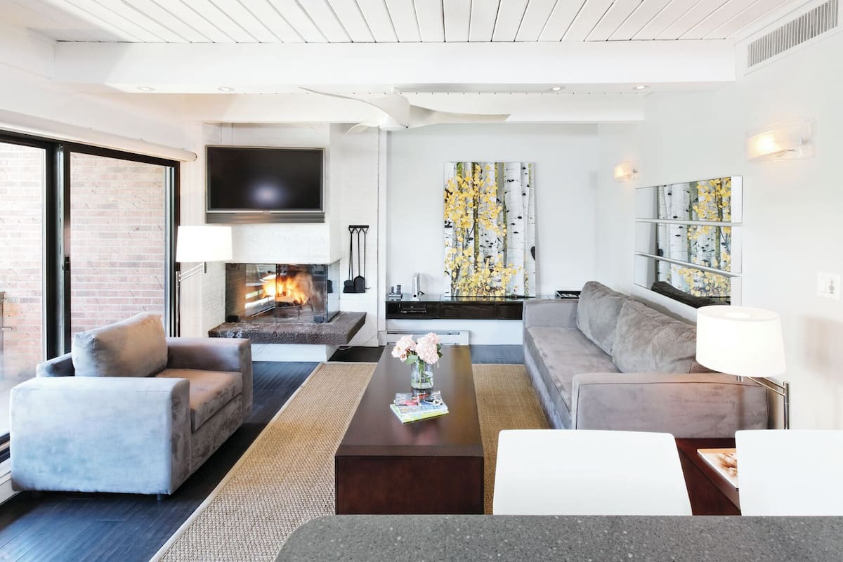 A modern living room with a fireplace, a sofa, a coffee table, and a TV mounted on the wall.