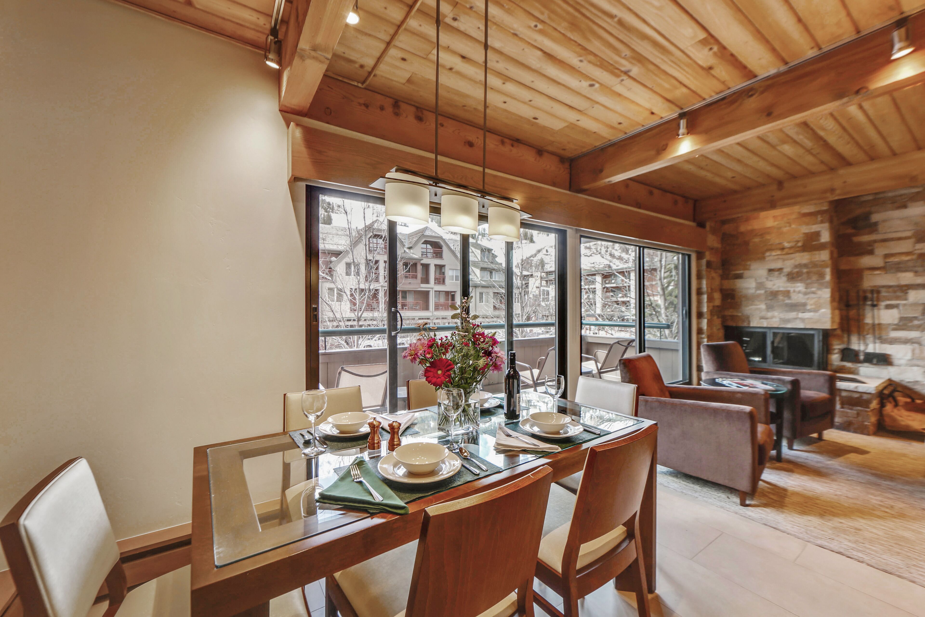 A dining area with a wooden table, chairs, and a large window offering a view of buildings.