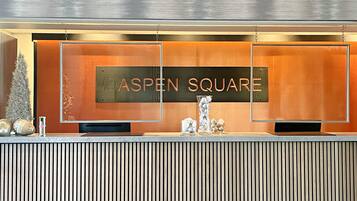 A reception desk with a sign reading "ASPEN SQUARE" and a vertical striped wall behind it.