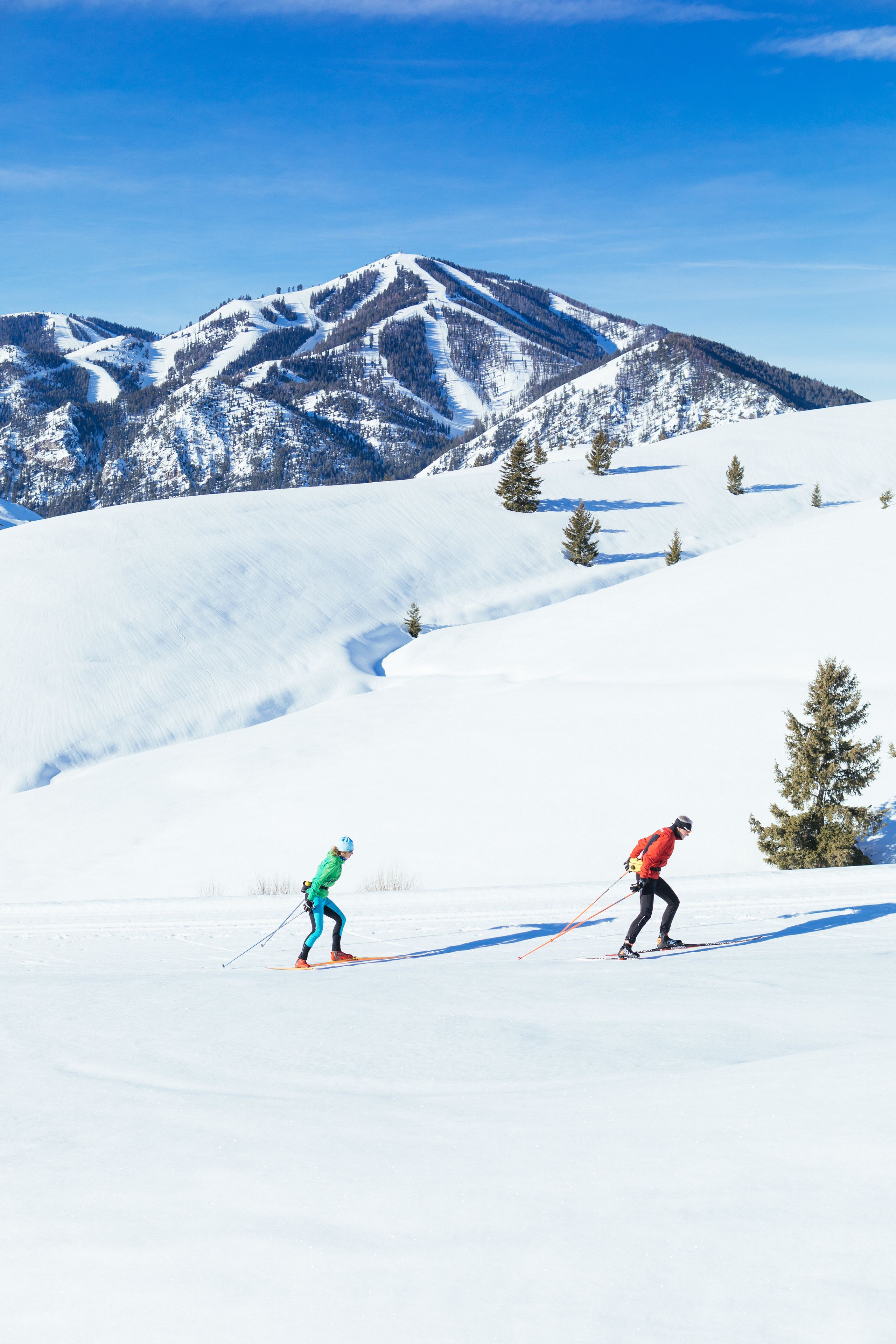 A snowy mountain landscape with two skiers.