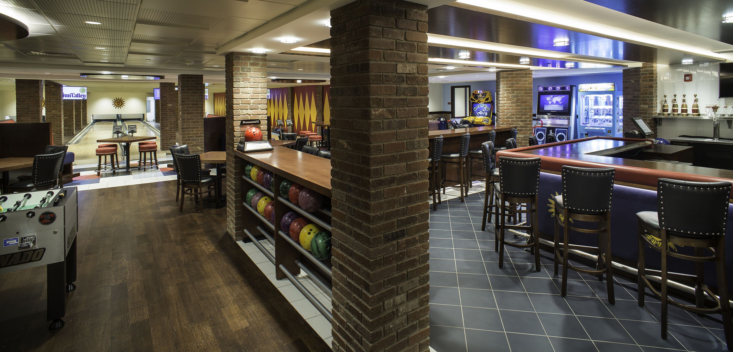 A bowling alley with a bar area, seating, and a bowling ball rack.
