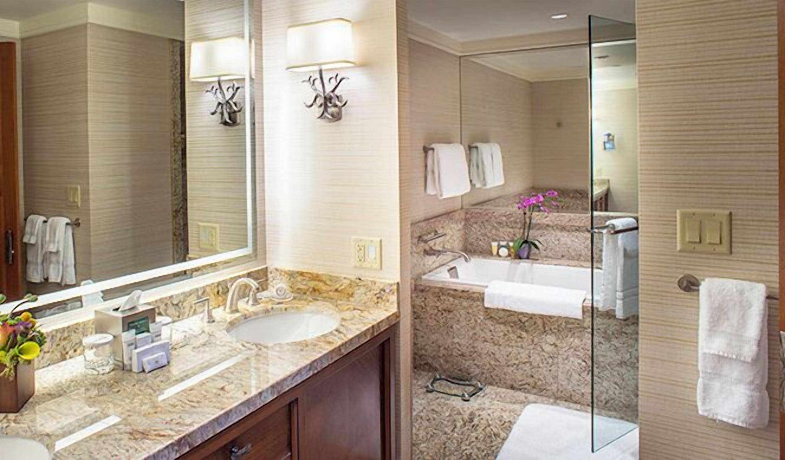 Ein modernes Badezimmer mit zwei Waschbecken, einem großen Spiegel und einer Duschkabine aus Glas.