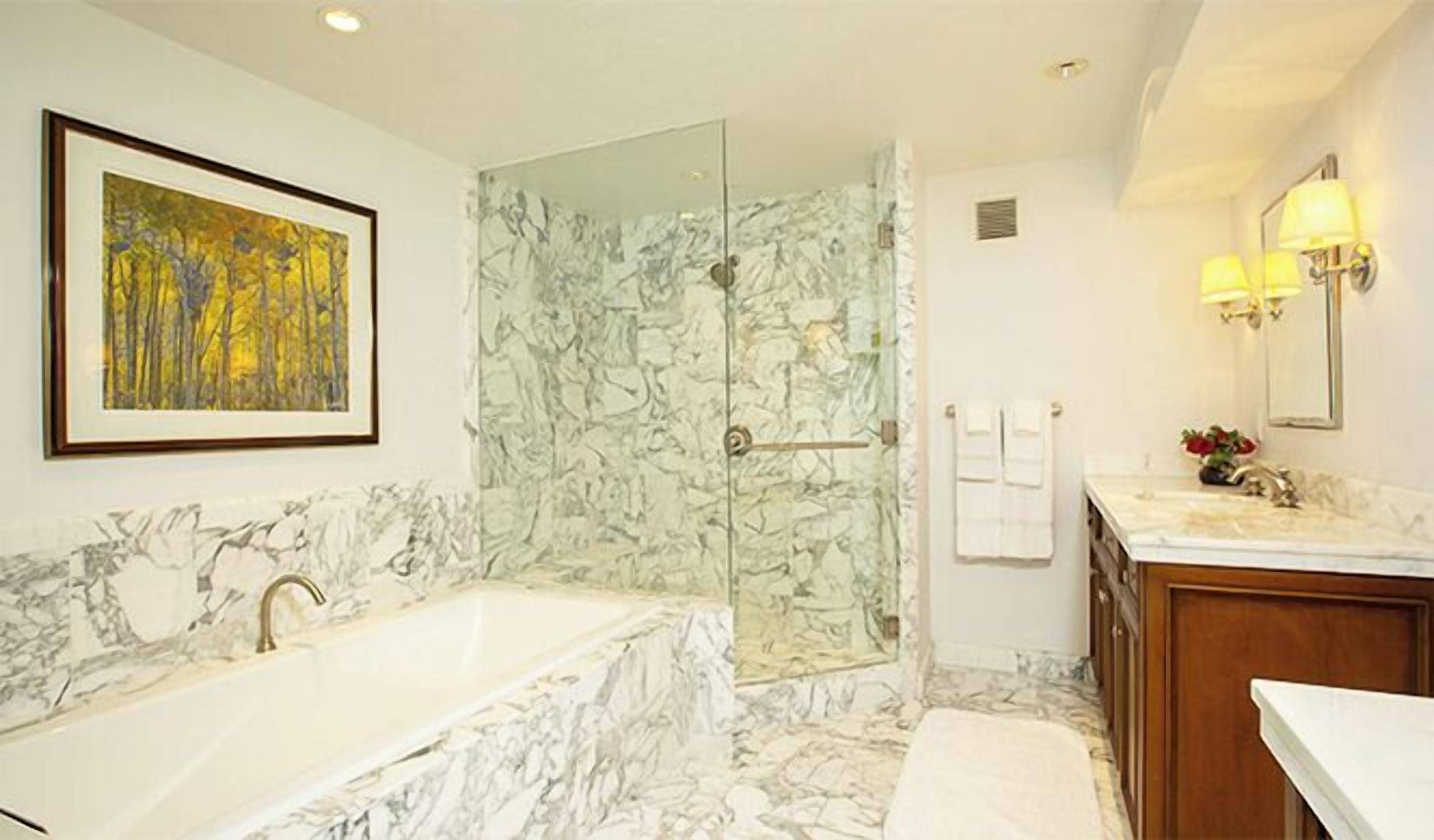 Une salle de bain dotée d’une grande baignoire, d’une douche à parois de verre et d’un sol en marbre.