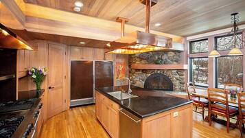 A kitchen with wooden cabinets, a stone fireplace, and a dining area with wooden chairs.