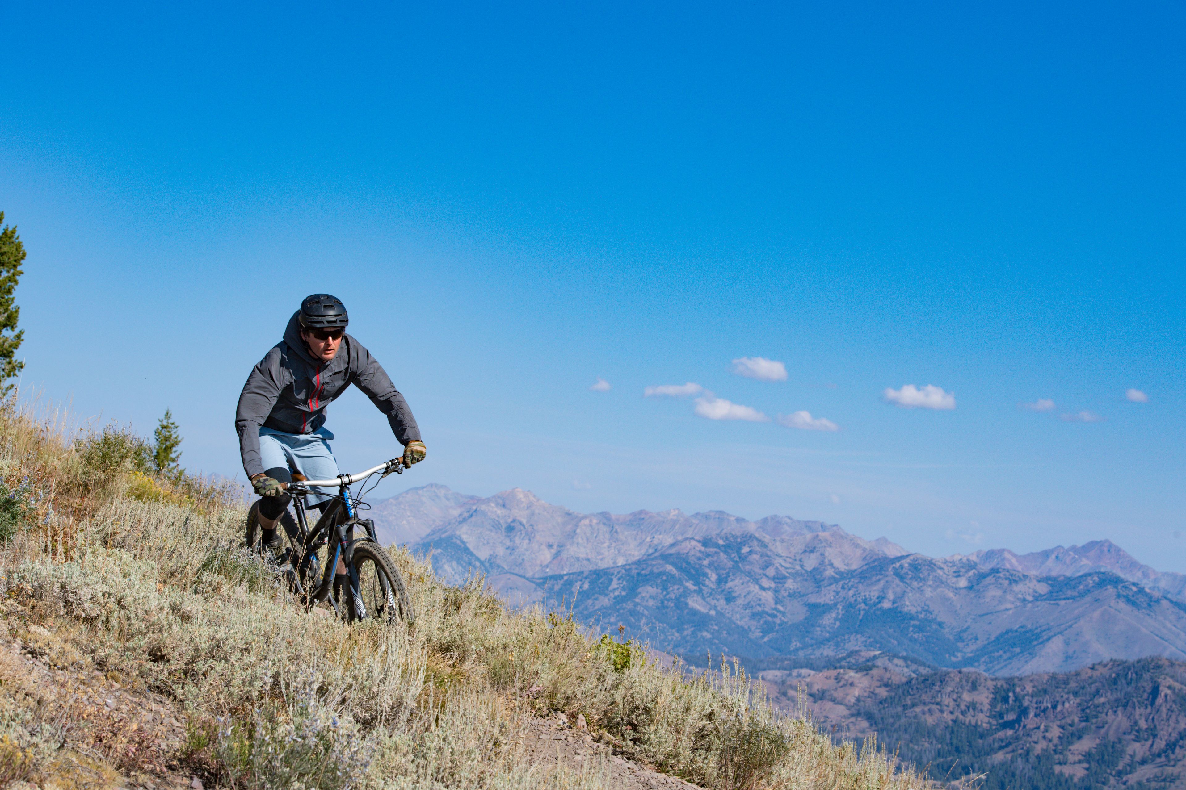 Ein Mountainbiker auf einem Trail vor einer Bergkulisse.
