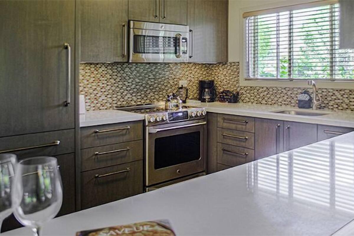 A kitchen with a microwave, oven, and coffee maker. There are two wine glasses on the counter.